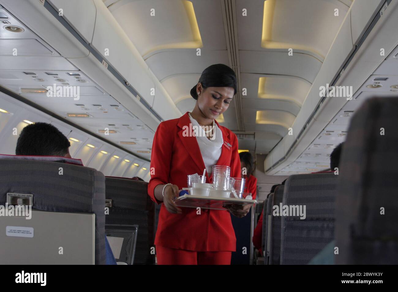 Un equipaggio di cabina che raccoglie il vetro dell'acqua usato su un aereo Best Airways. Bangladesh Foto Stock