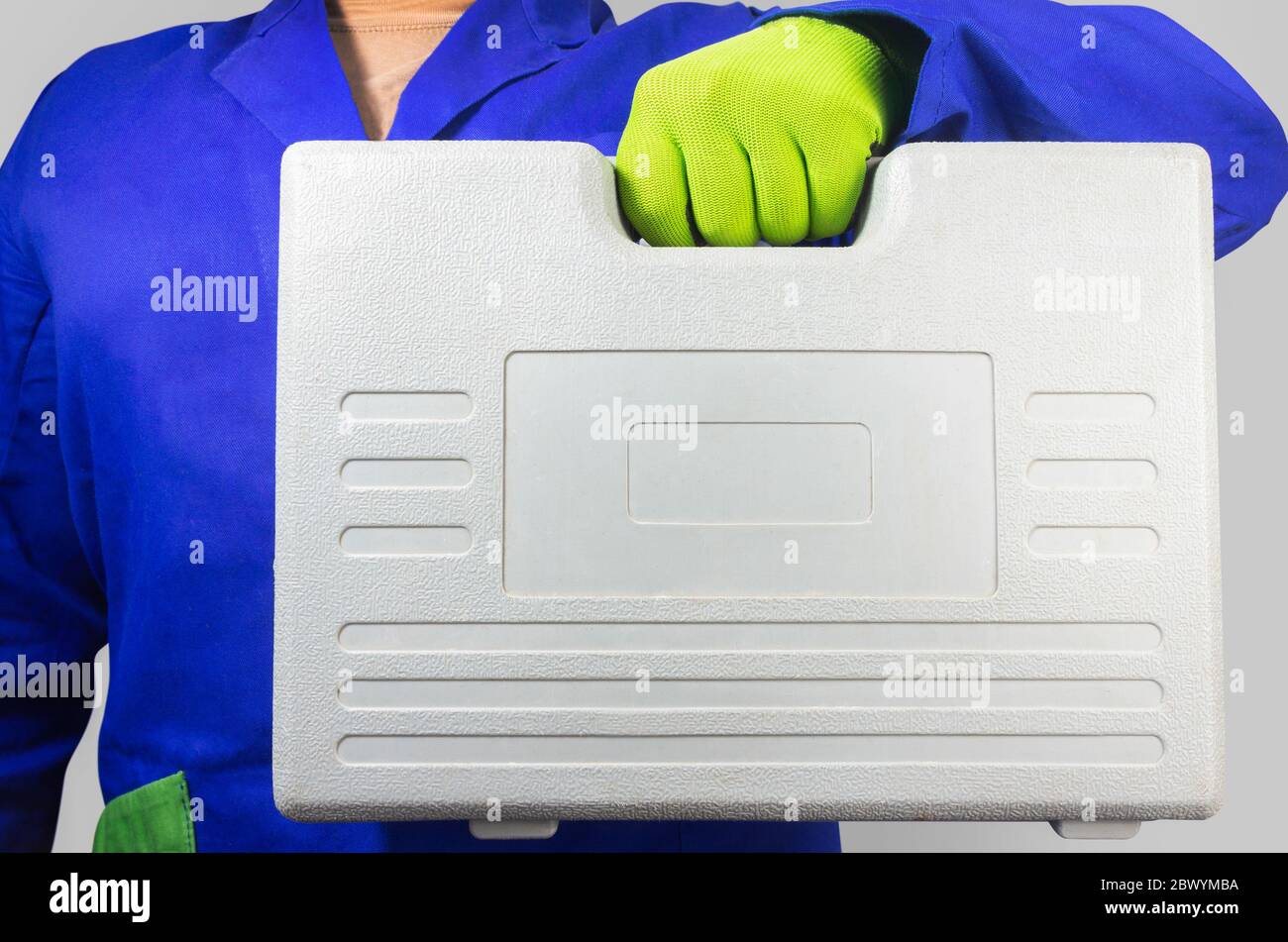 Foto di un lavoratore in abito blu con guanti che tengono una valigetta grigia. Foto Stock