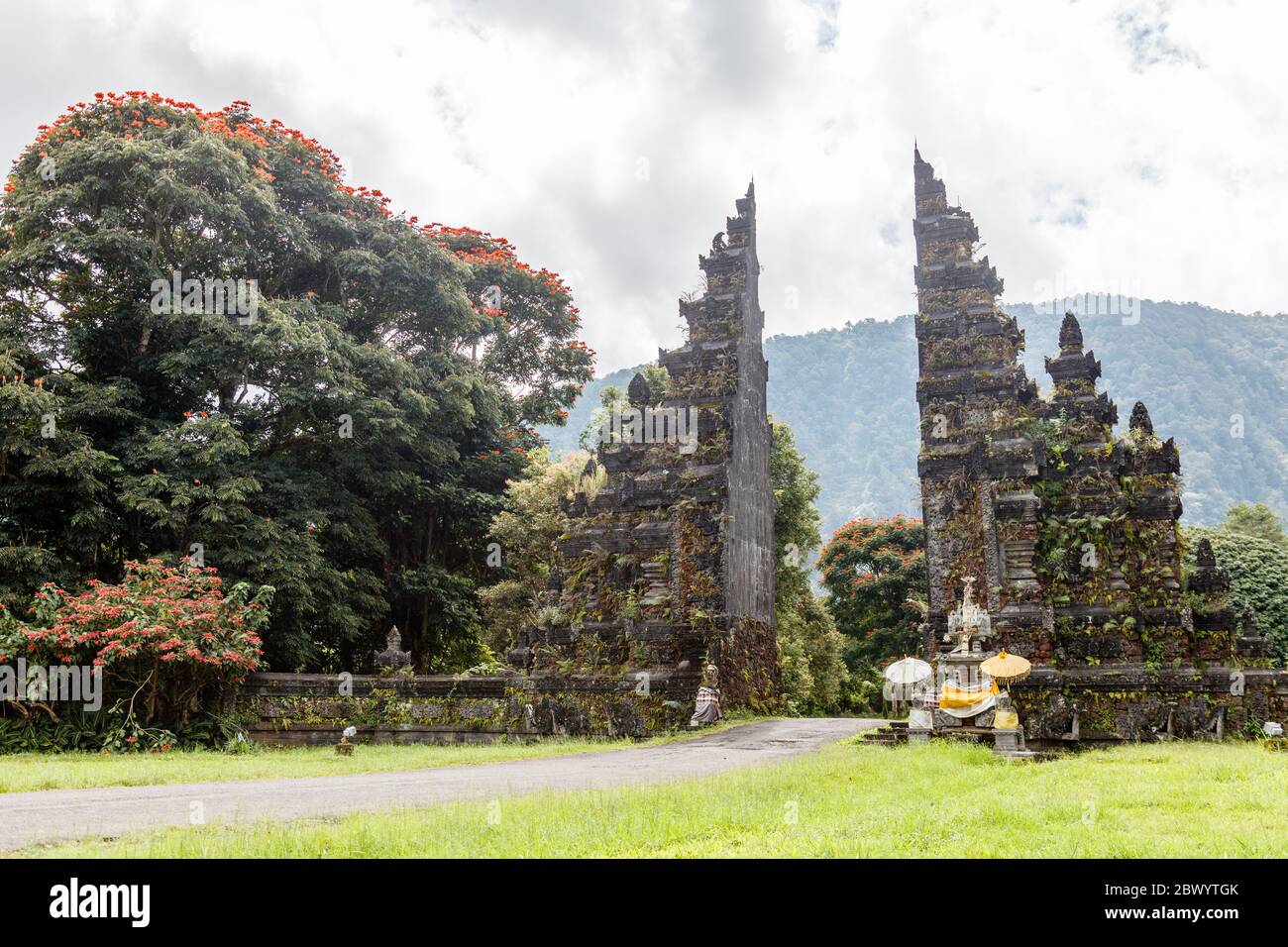 Tradizionale balinese a porte divise candi bentar. Bedugul, Gianyar, Bali, Indonesia. Spathodea Campanulata, o tulipani africani intorno. Foto Stock