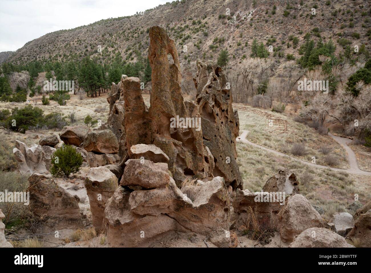 NM00458-00...NUOVO MESSICO - rocce tenda erose che si affacciano sui resti della comunità di Tyuonyi nel Canyon Frijoles al Bandelier National Monument. Foto Stock