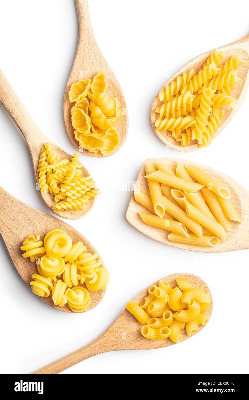 Vari tipi di pasta italiana cruda in cucchiai di legno isolati su fondo bianco. Foto Stock