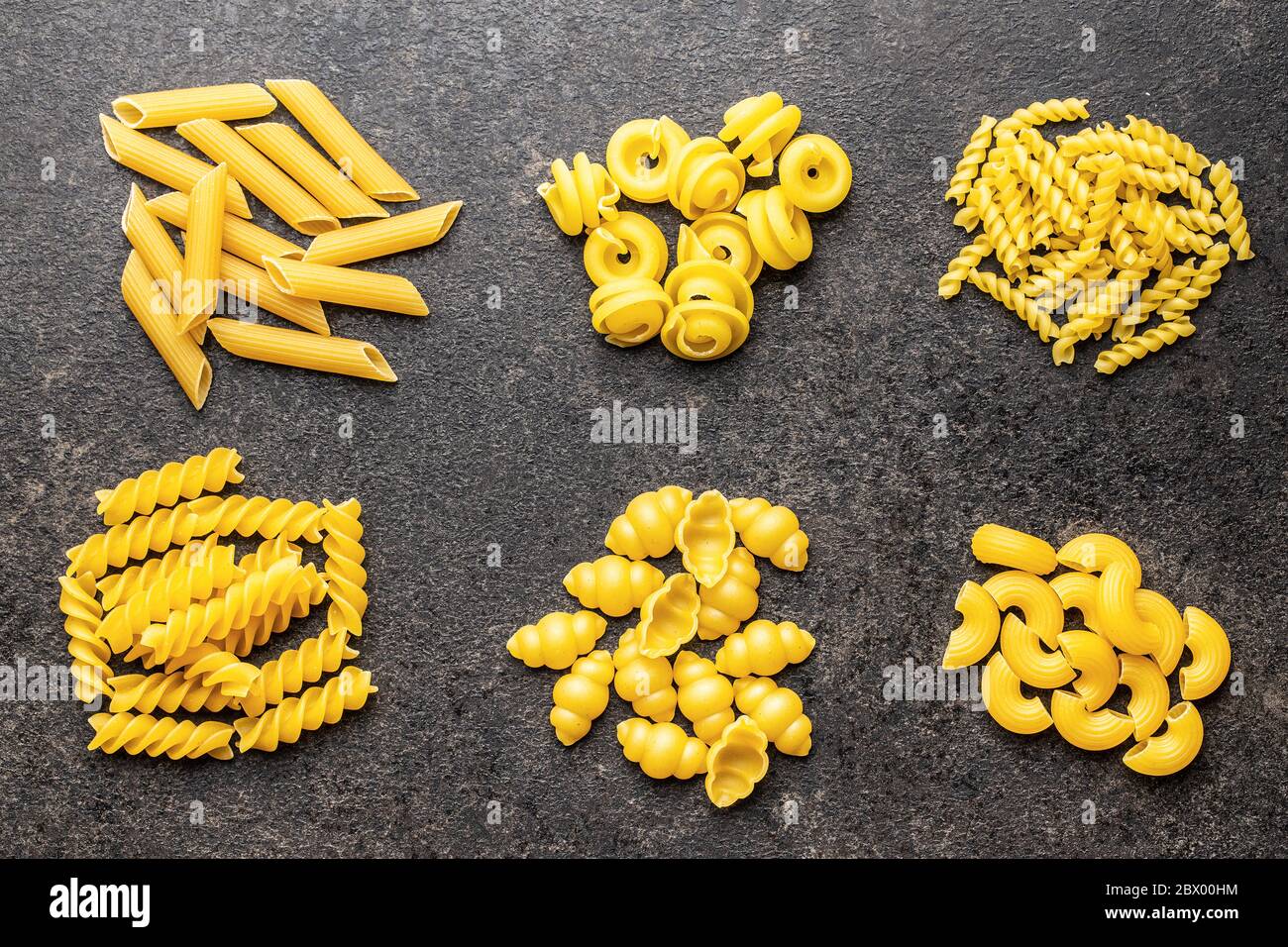Vari tipi di pasta italiana cruda su tavola nera. Vista dall'alto. Foto Stock