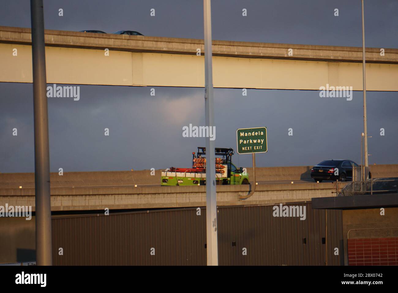 Camion e auto sul cavalcavia dell'autostrada con cartello verde Next uscita per Mandela Parkway. Sistema di trasporto su strada. West Oakland, California, Stati Uniti Foto Stock