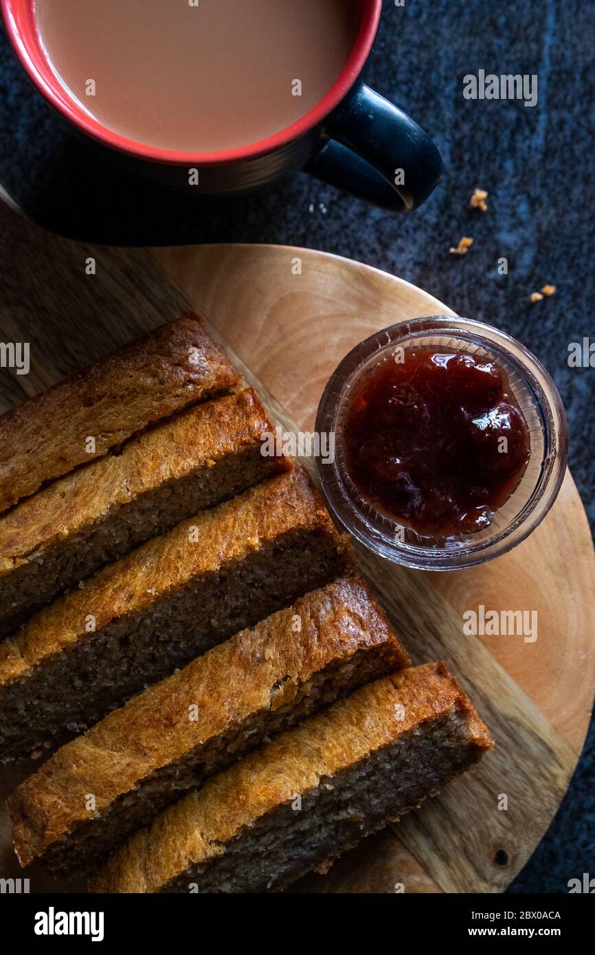 Teacake di pane di banana su un piatto con marmellata e una tazza di tè / caffè Foto Stock