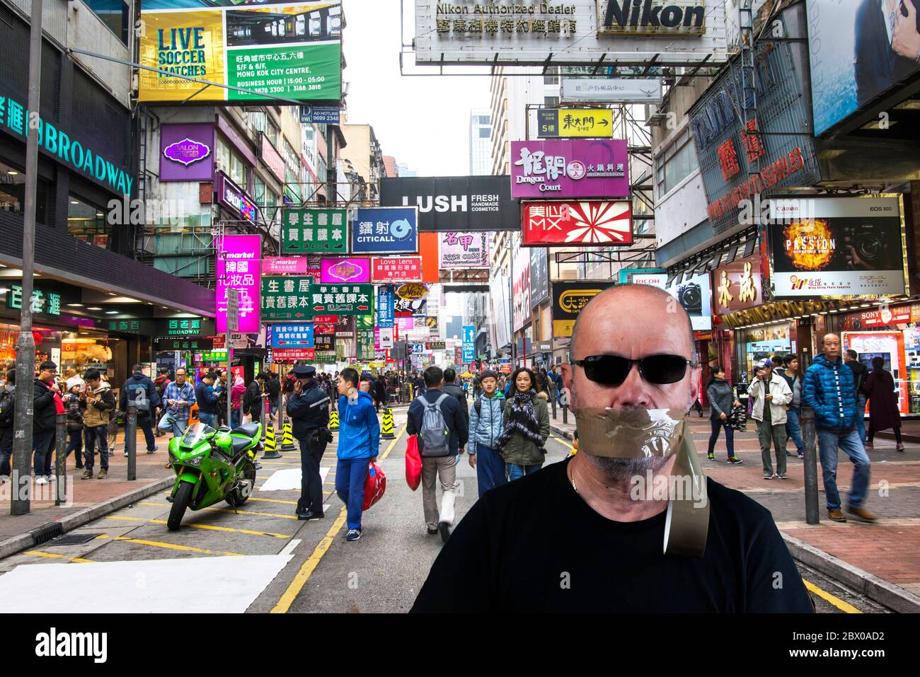 Un uomo con gli occhiali in una strada a Hong Kong con la bocca coperta di nastro Foto Stock