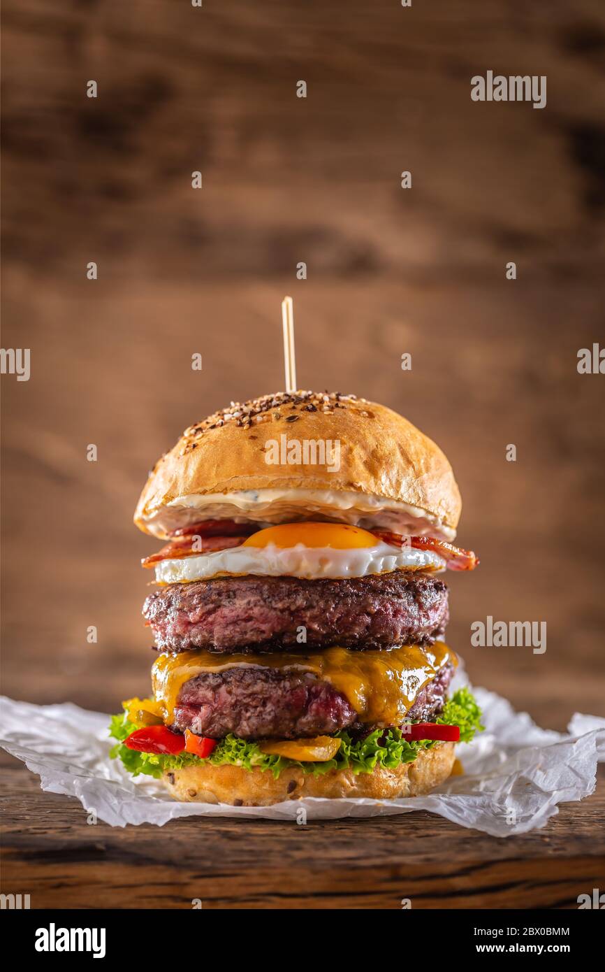 Hamburger di manzo doppio con formaggio, uova fritte, pancetta, insalata e peperoni Foto Stock