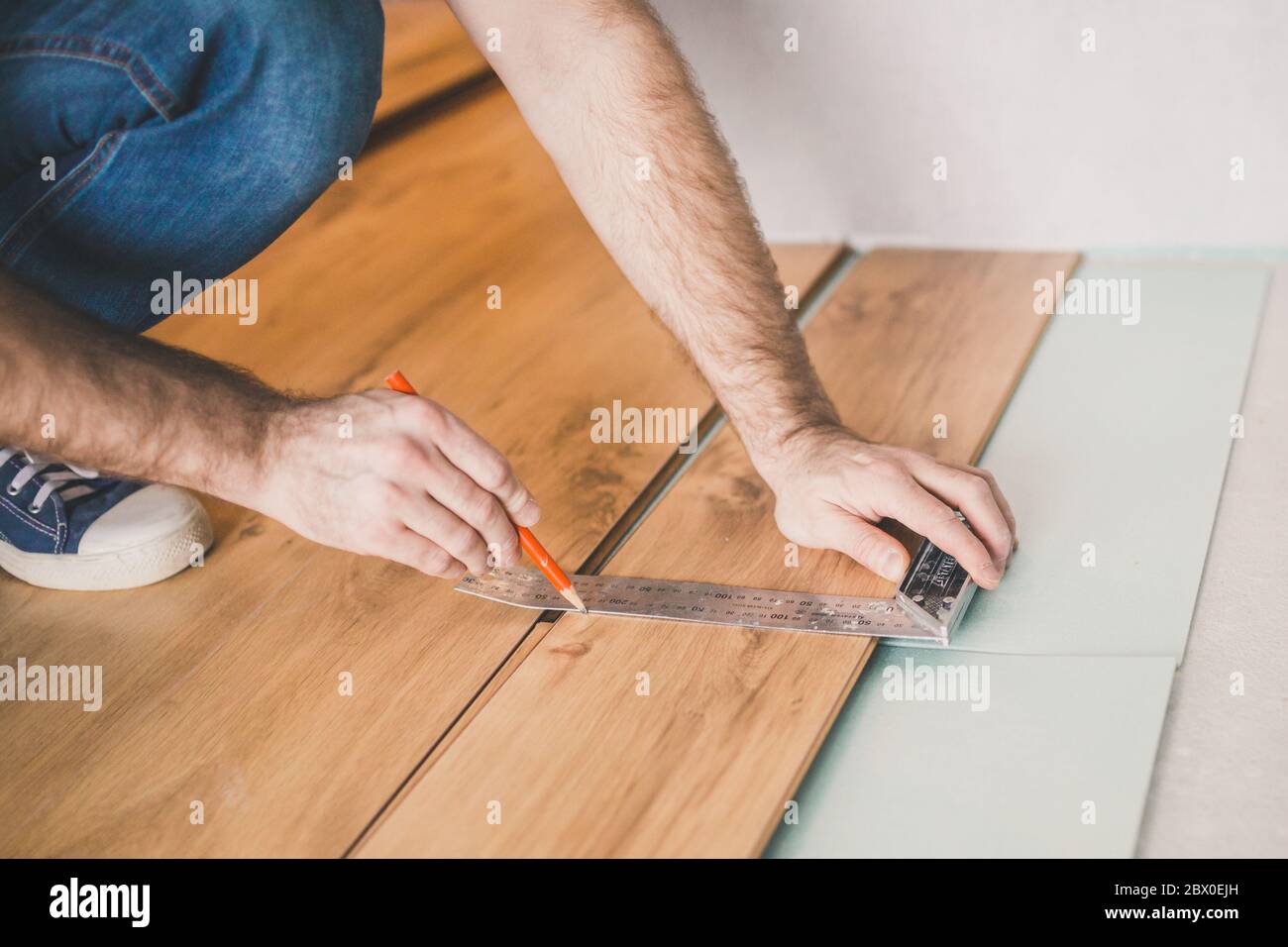 Installazione professionale della pavimentazione - il master contrassegna il pannello laminato per il taglio Foto Stock