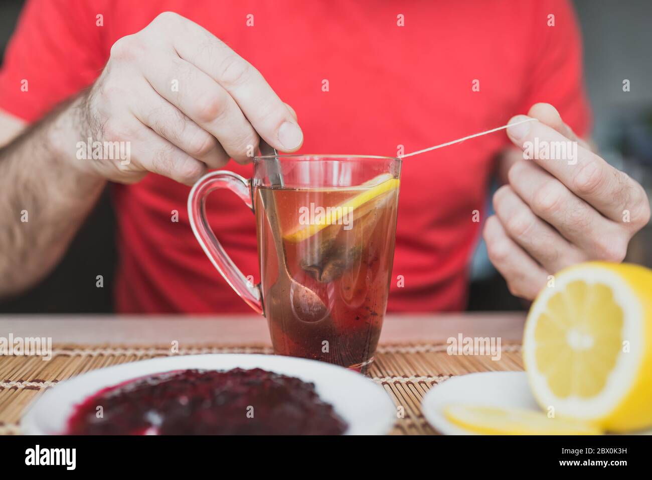 Tè verde in una tazza di vetro trasparente con marmellata e limone - tè allo zenzero Foto Stock