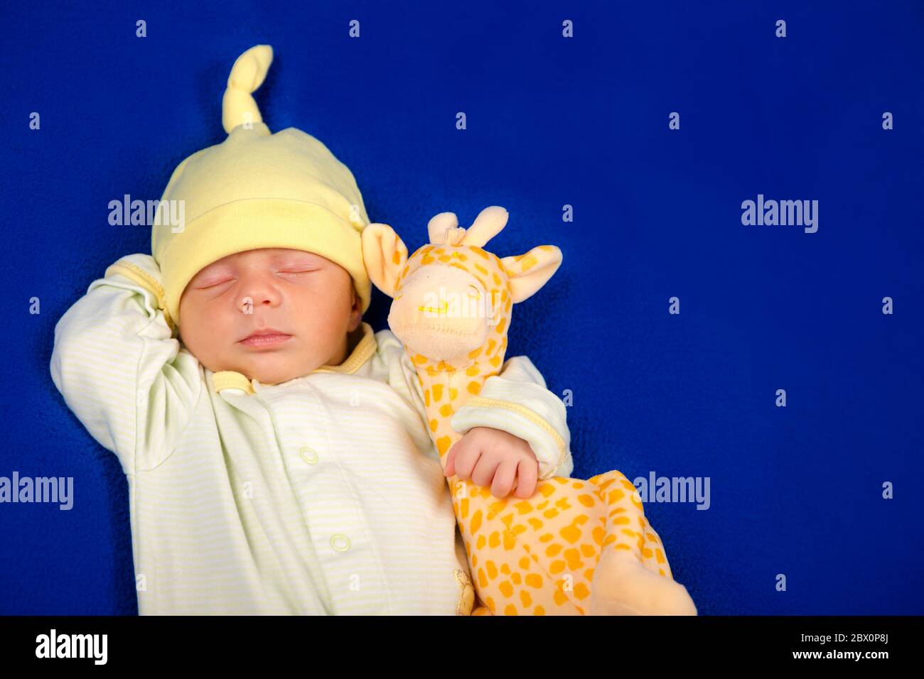 Adorabile bambino sdraiato su una coperta blu con giraffa giocattolo. Ragazzo o ragazza Foto Stock