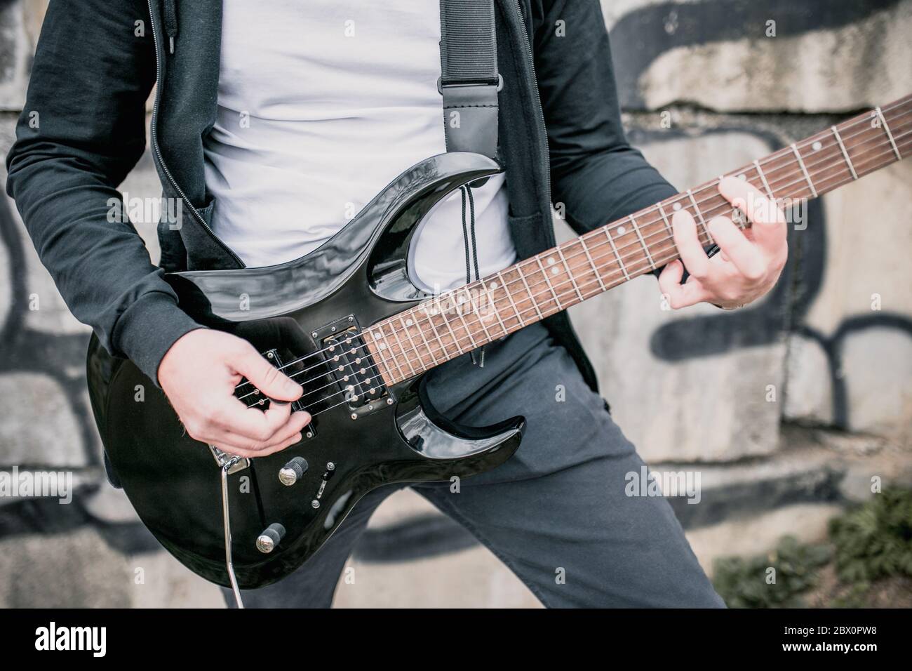 Uomo con una chitarra elettrica nera all'aperto - musica rock blues Foto Stock