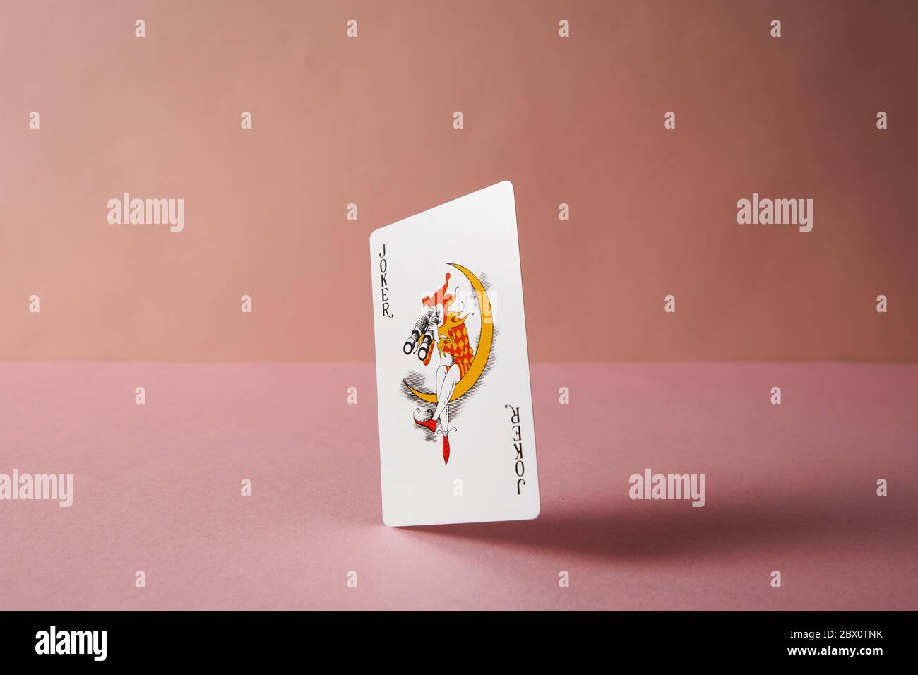 Joker carta da gioco su sfondo rosa. Foto Stock