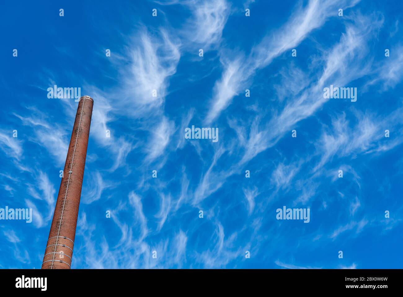 Cielo blu con nuvole di circo, filigrane nuvole di ghiaccio ad alta quota, porti di clima più caldo, camini, emissioni Foto Stock