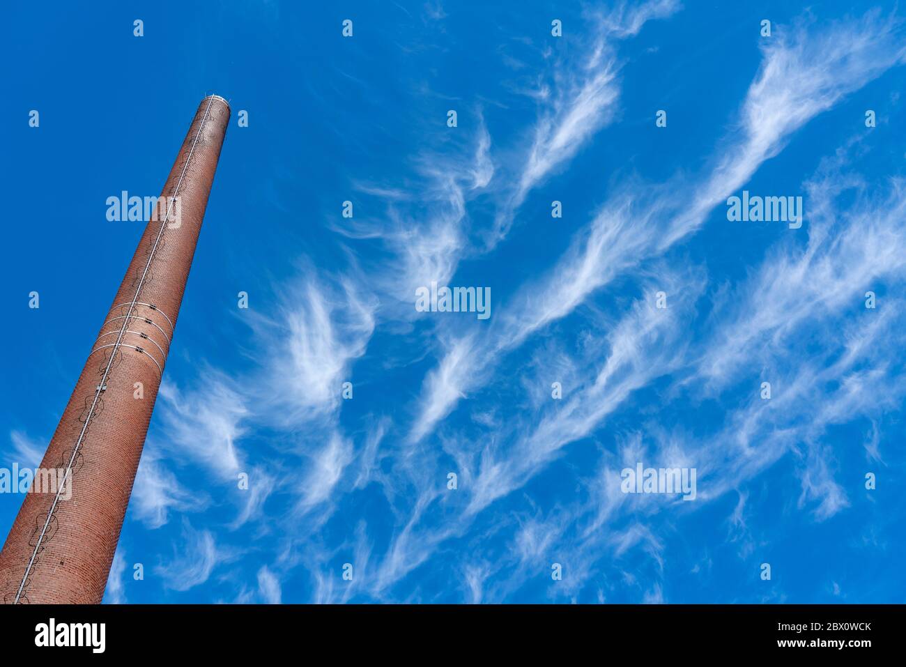 Cielo blu con nuvole di circo, filigrane nuvole di ghiaccio ad alta quota, porti di clima più caldo, camini, emissioni Foto Stock
