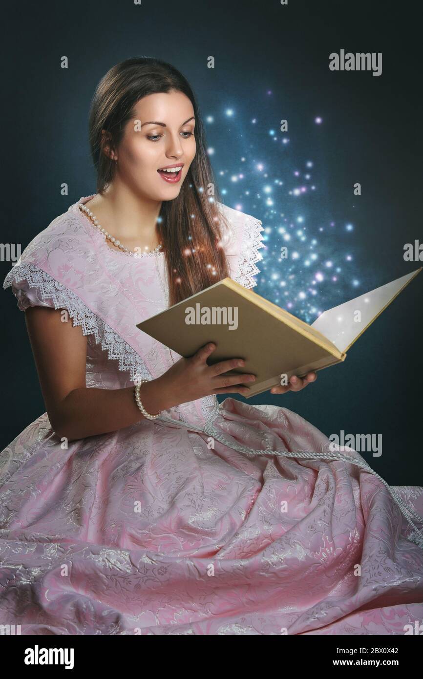 Bella donna vestita come una principessa fiabesca con libro magico Foto Stock