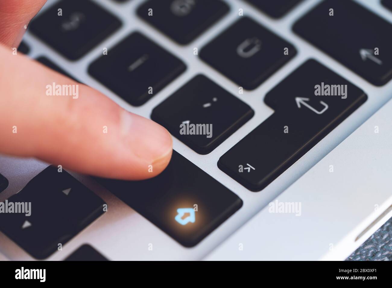 Primo piano del dito dell'uomo che tocca il tasto Maiusc lettera sulla tastiera del computer nero Foto Stock