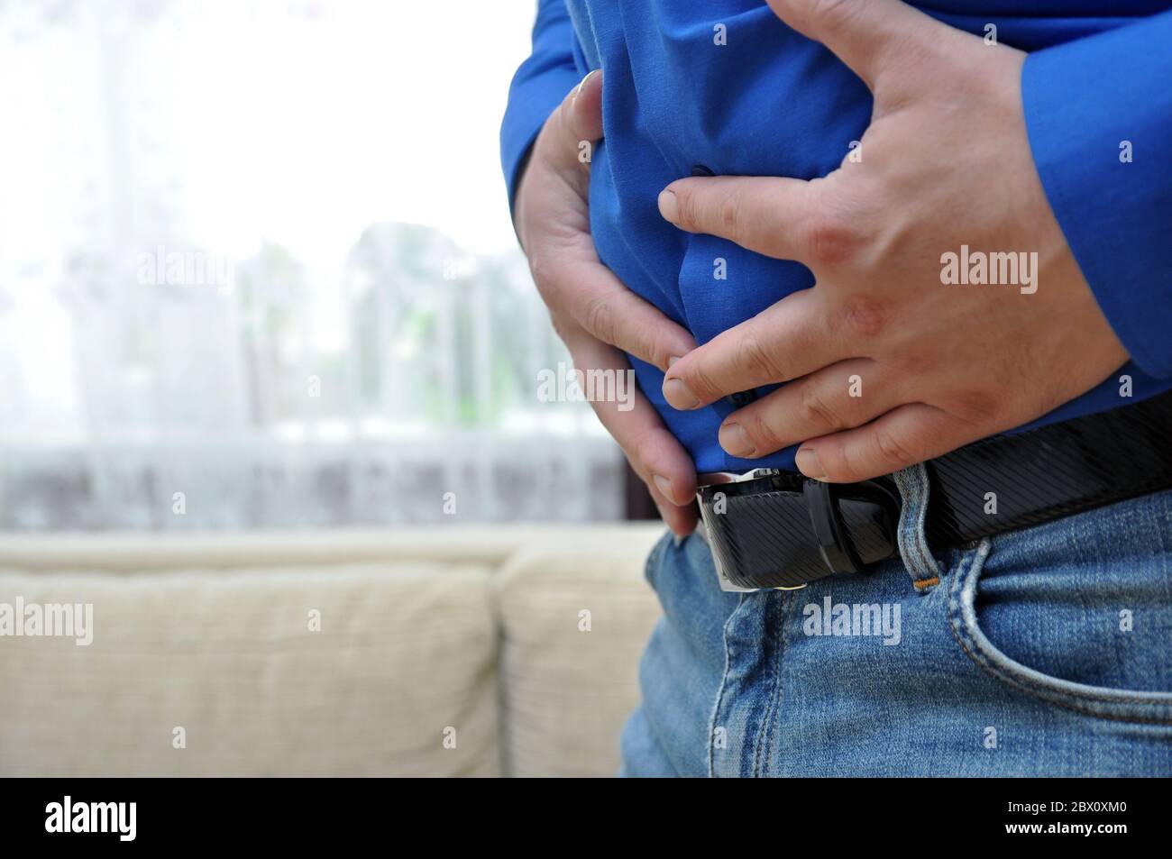 Un uomo in una camicia blu soffre di dolore addominale. Disturbi intestinali. Foto Stock
