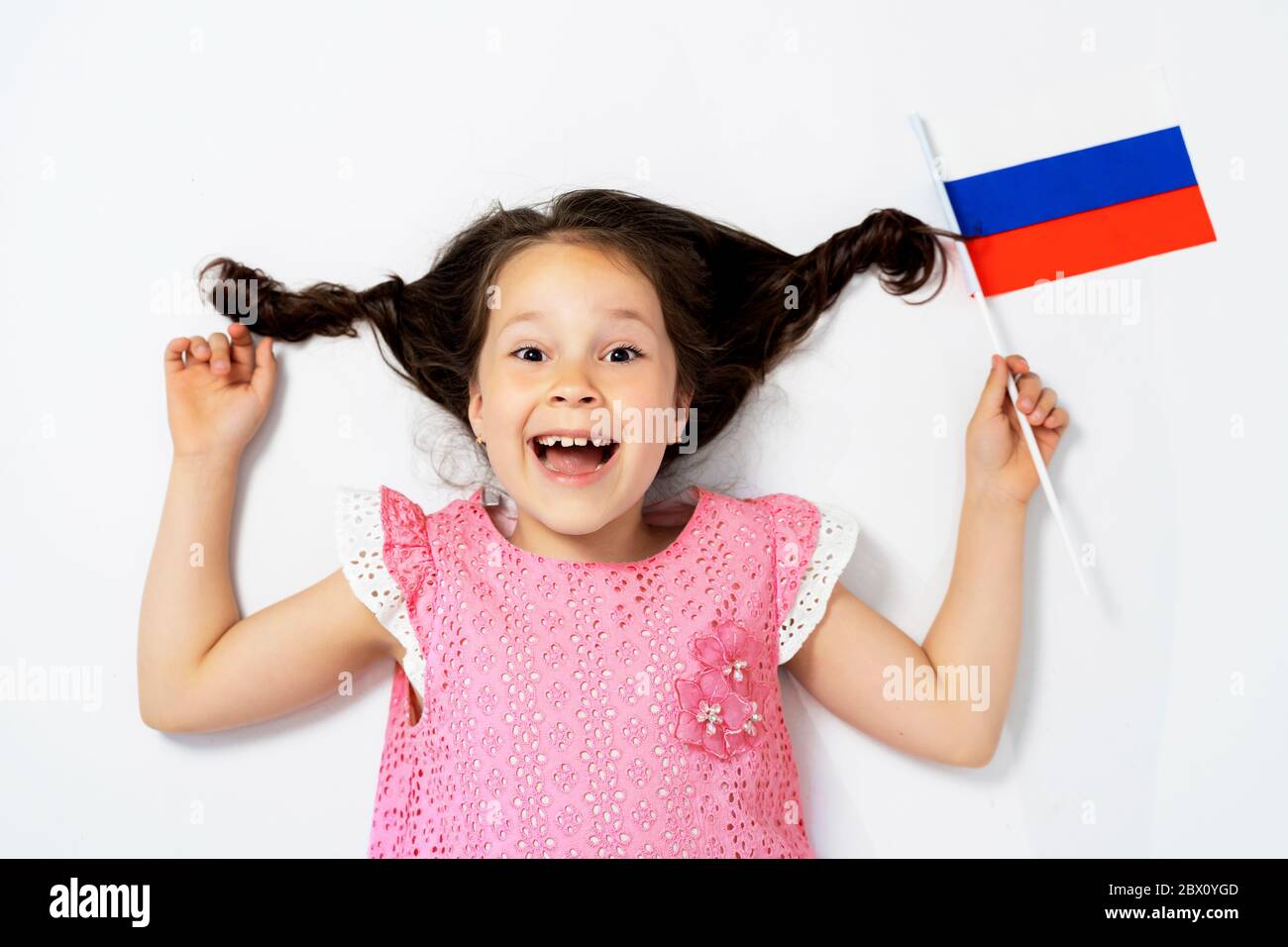 Una bella ragazza si trova su uno sfondo bianco accanto alla bandiera della Russia, la vista dall'alto. Foto Stock