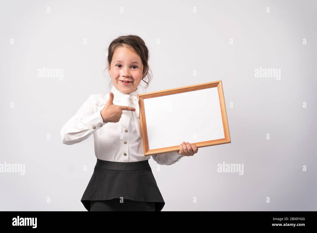 la ragazza della scuola di primo grado tiene un foglio bianco per iscrizione Foto Stock