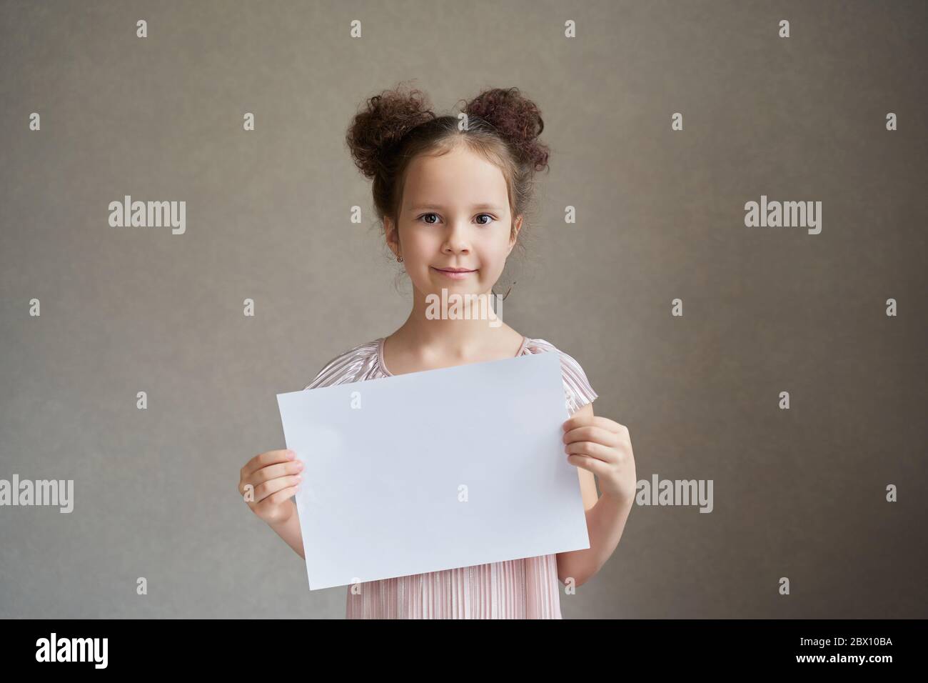 una bella ragazza con due code tiene un pezzo bianco di carta per scrittura Foto Stock