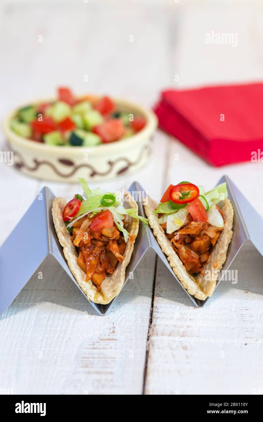 Due tacos vegan trainati con jackfruit realizzati con tortillas di mais morbido in un supporto per tortilla. Foto Stock