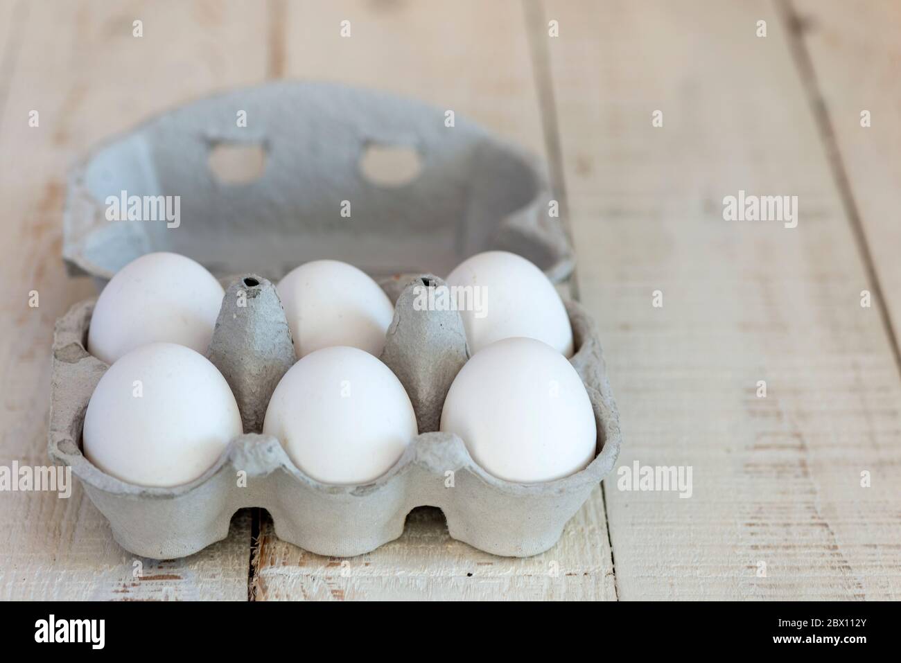 Sei uova bianche sgusciate in un cartone di cartone. Foto Stock