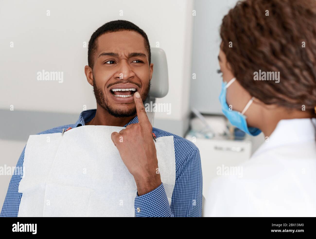 Ragazzo nero che visita dentista, mostrando medico denti dolorosi Foto Stock
