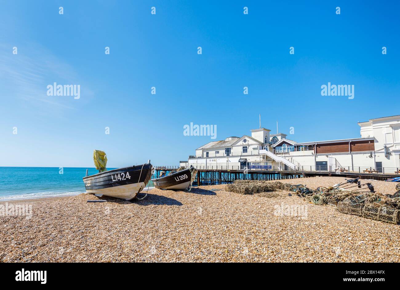 Piccole barche da pesca spiaggiate sulla ghiaia con pentole di aragosta presso il molo di Bognor Regis, una cittadina balneare nel Sussex occidentale, costa meridionale dell'Inghilterra Foto Stock