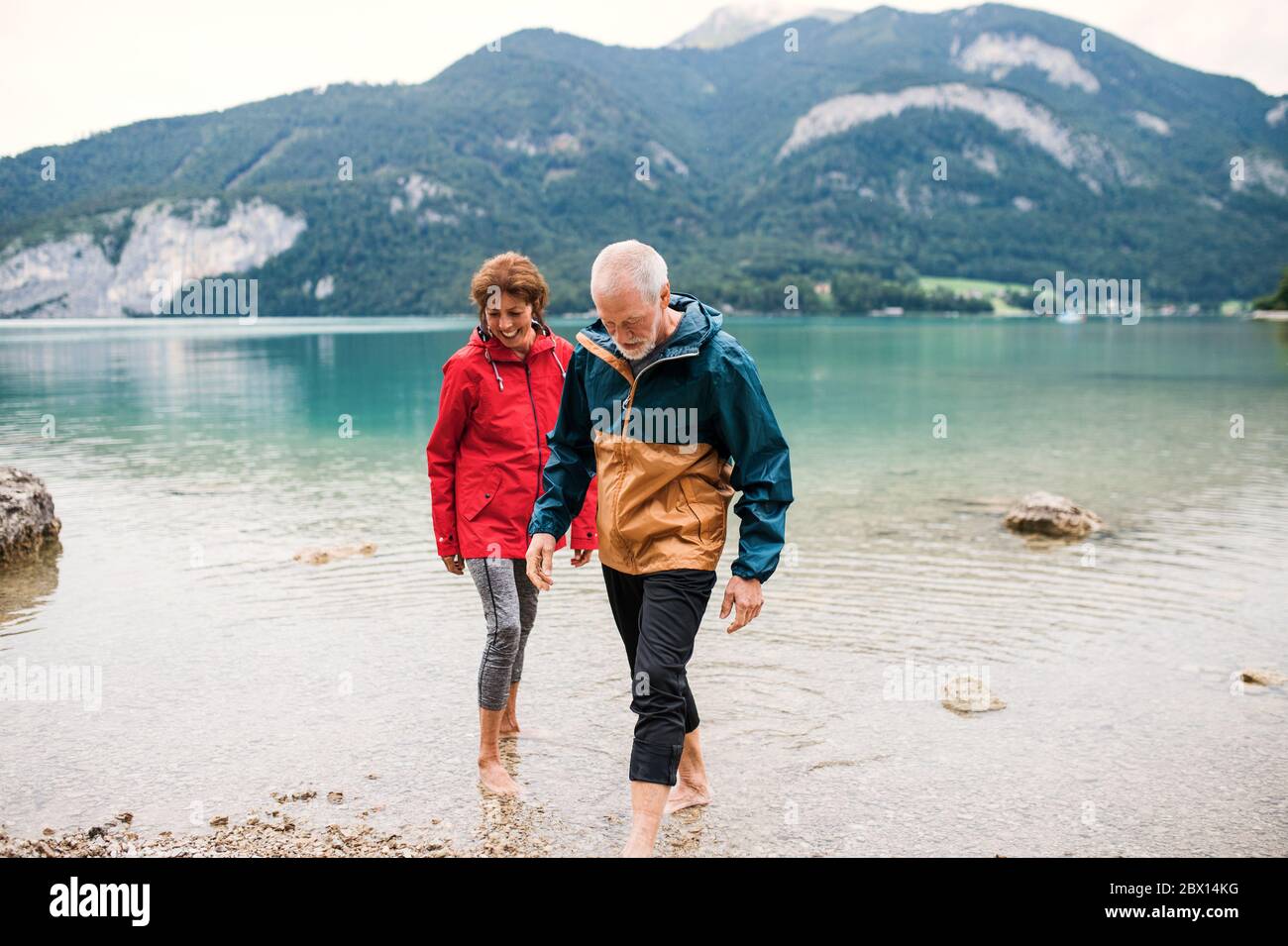 Una coppia di anziani pensionati escursionisti in piedi nudi in lago in natura. Foto Stock