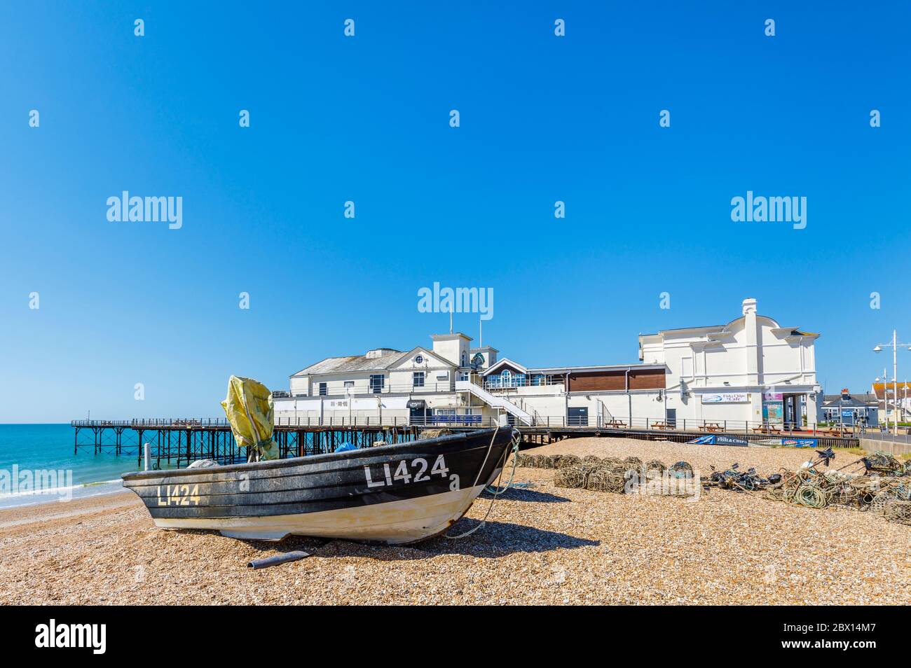 Una barca da pesca sulla spiaggia di ciottoli sassosi presso il molo sul lungomare di Bognor Regis, una cittadina di mare nel Sussex occidentale, costa meridionale dell'Inghilterra Foto Stock