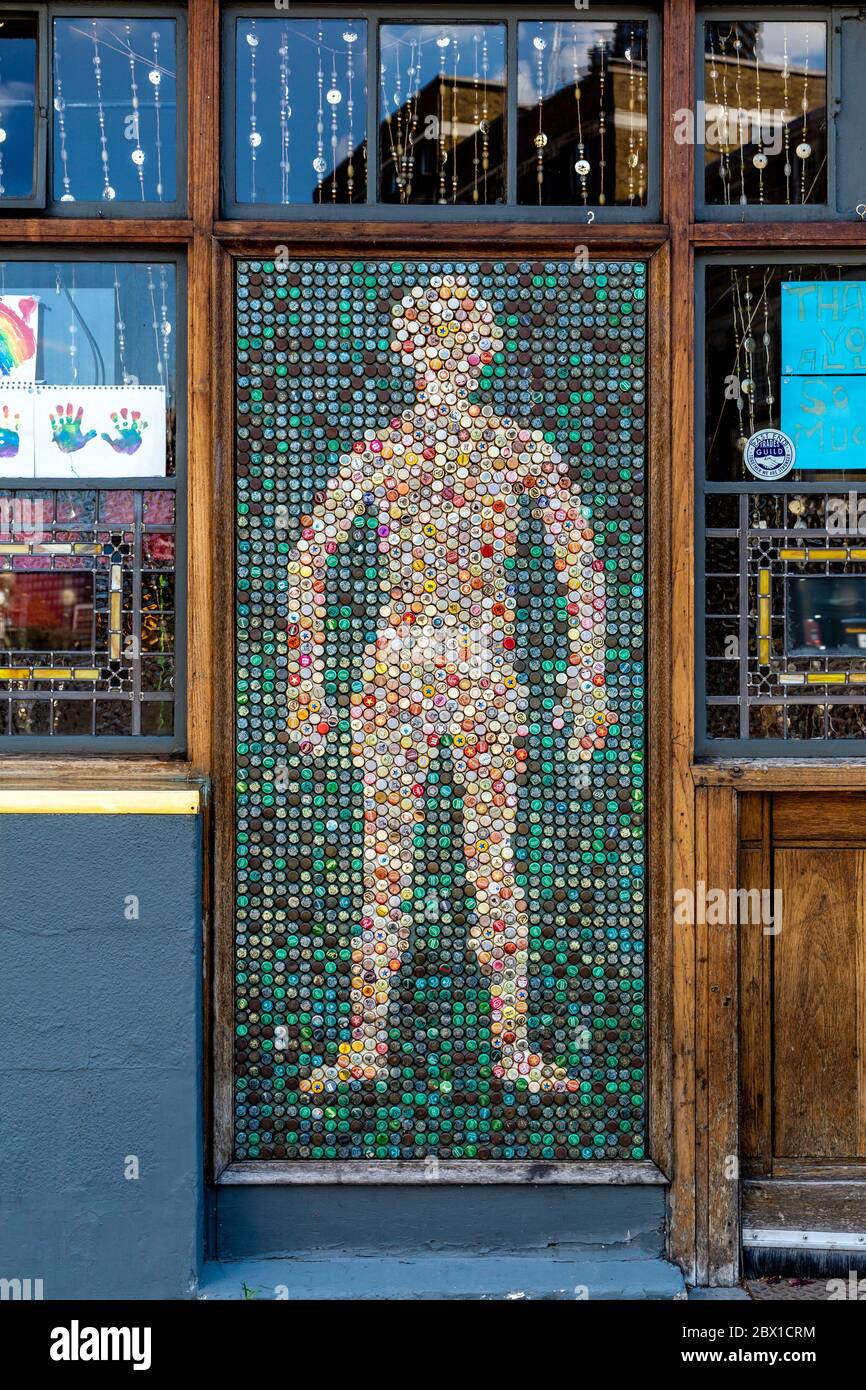 Silhouette umana fatta di vecchi tappi in metallo sulla facciata del Golden Heart pub, Spitalfields, Londra, UK Foto Stock