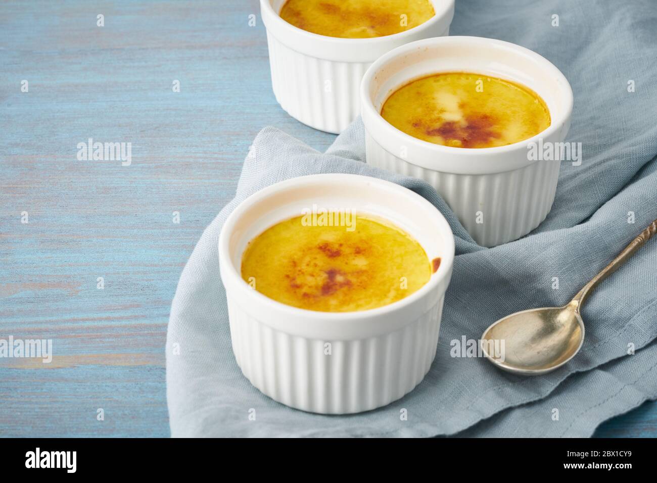 Crema catalana, dessert spagnolo in tre ramekin su tavolo blu, spazio copia Foto Stock