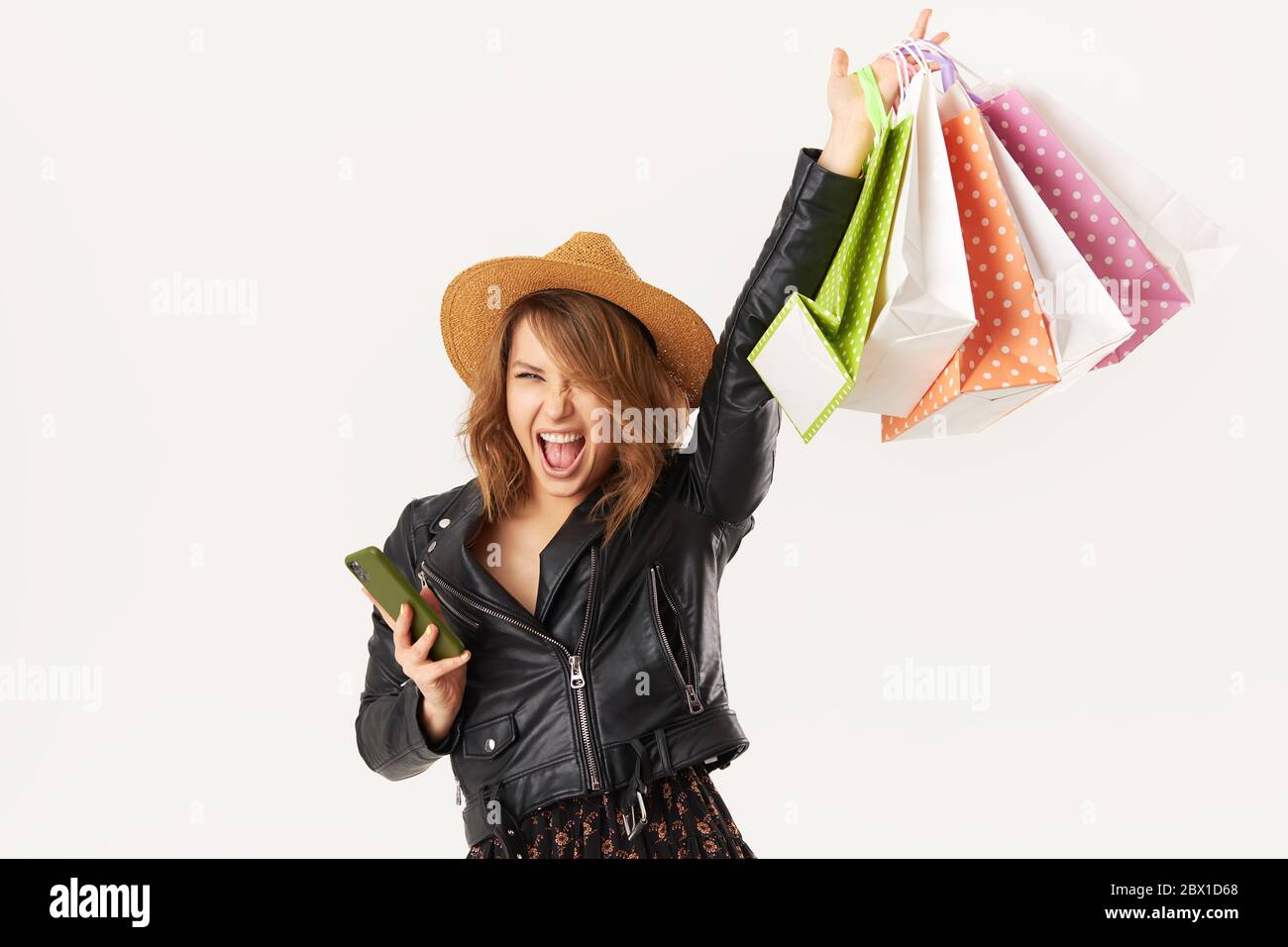 Blogger femminile che visualizza un profilo sulle reti su un telefono cellulare tramite Internet 5G. Giovane donna con borse di shopping fa acquisti attraverso il online Foto Stock