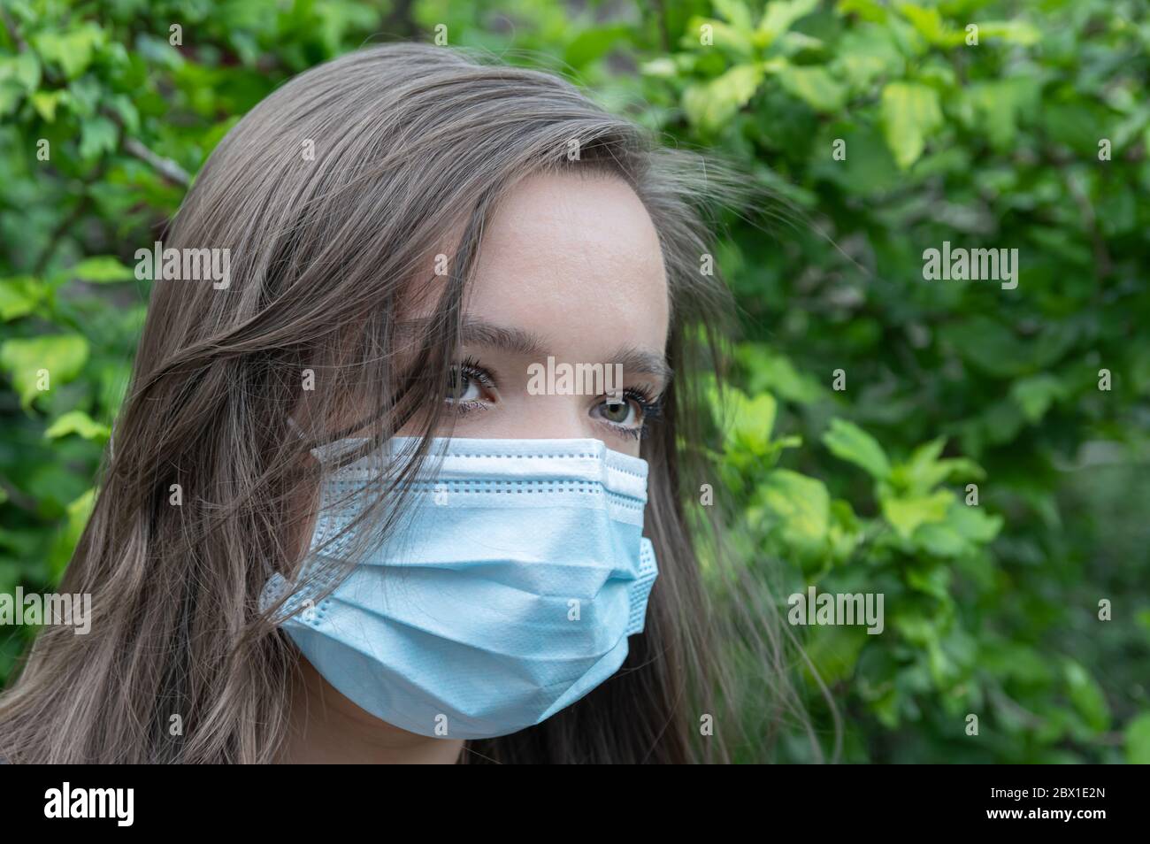 Ritratto di giovane donna caucasica con maschera protettiva sul viso, protezione contro virus e malattie. Foto Stock