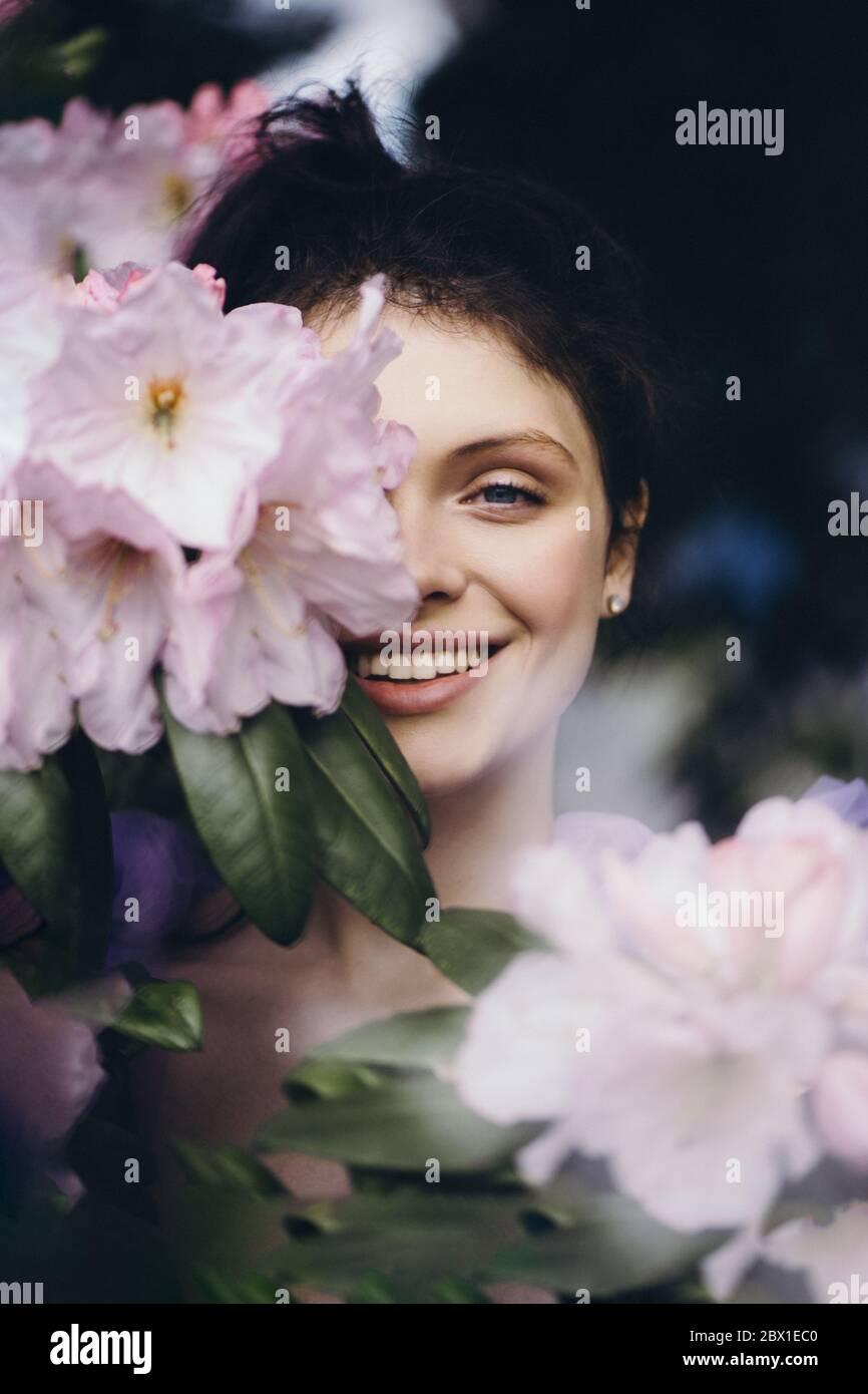 Bella giovane donna sorridente con fiori il giorno d'estate. Foto Stock