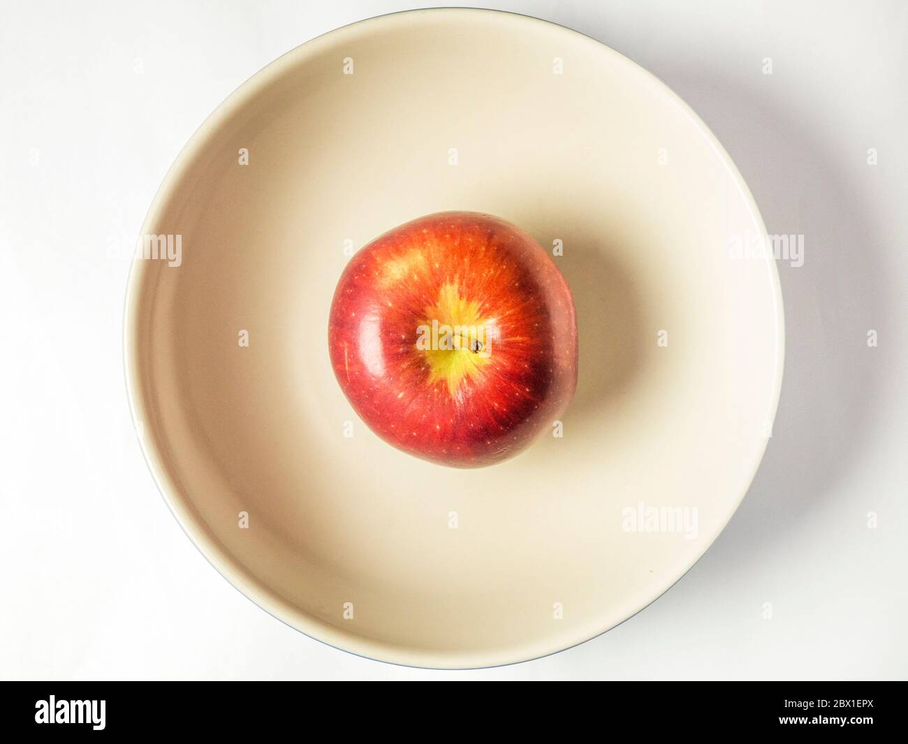 Una singola Braeburn mangiare mela in una grande ciotola dall'alto isolato su uno sfondo bianco Foto Stock