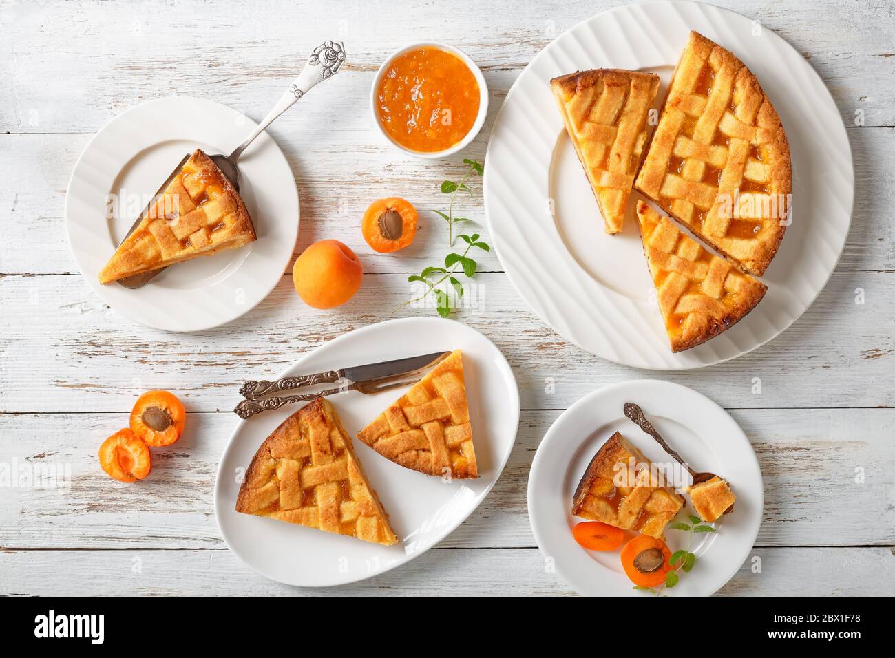 torta di frolla di albicocca tagliata con crosta di torta a graticcio su piatti bianchi su un tavolo rustico in legno, piatto Foto Stock