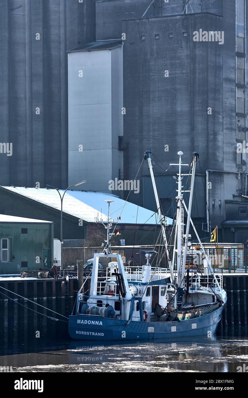 Il tagliatore di pesca Madonna della penisola di Nordstrand è ormeggiato nel porto di Husum di fronte ad un'enorme torre di silo. Foto Stock