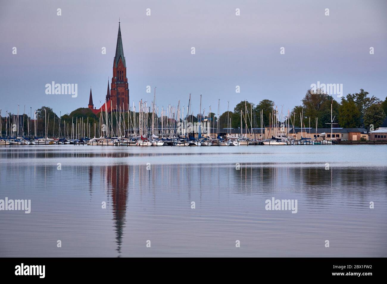 La cupola di San Petri dello Schleswig e le feste del Club di vela di Schlei visto dal porto di Wiking durante il crepuscolo. Foto Stock