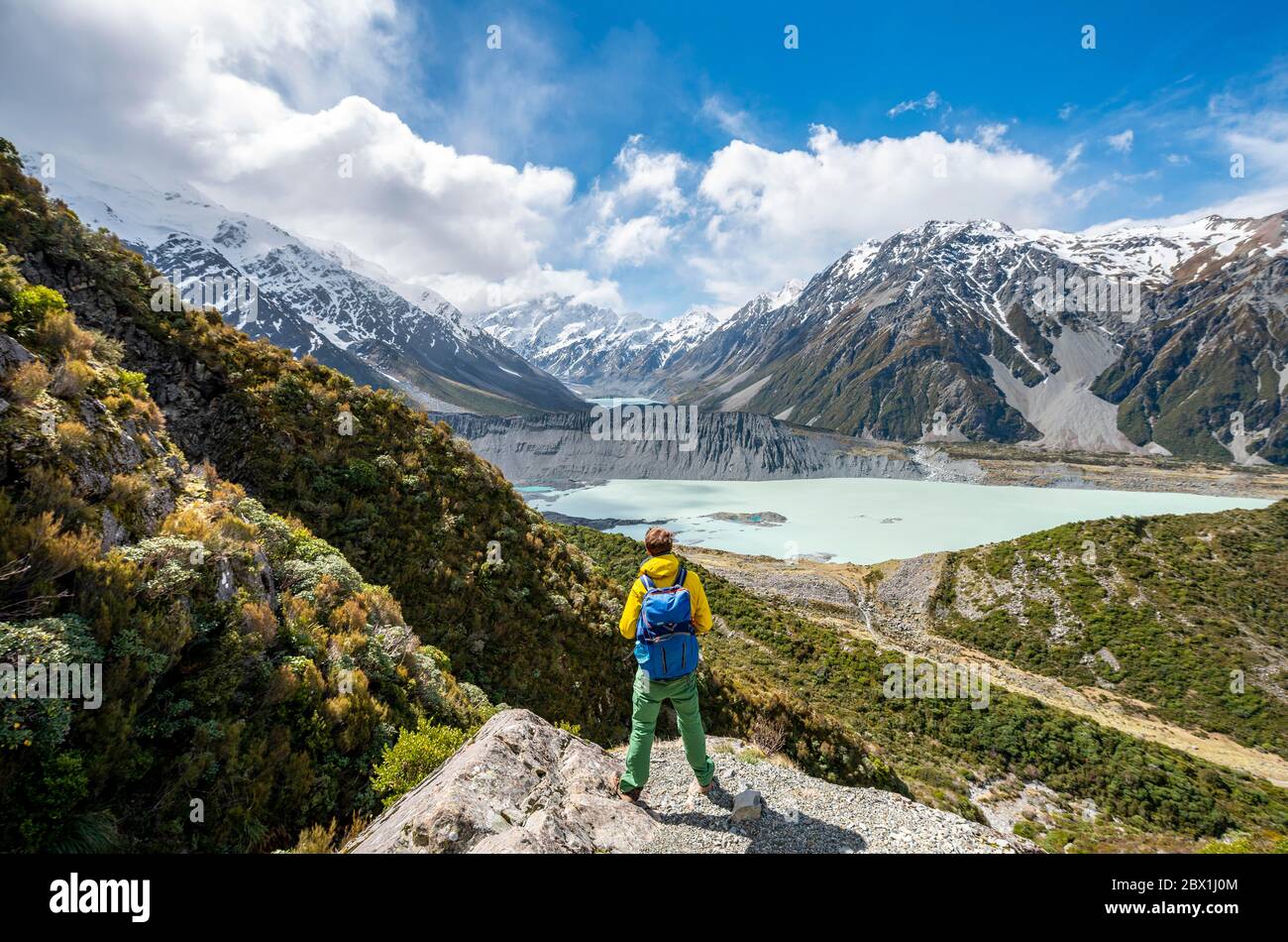 L'escursionista si erge su rocce, con vista sulla Hooker Valley dal Sealy Tarns Track, sui laghi glaciali Mueller Lake e Hooker Lake, sul Mount Cook National Park Foto Stock