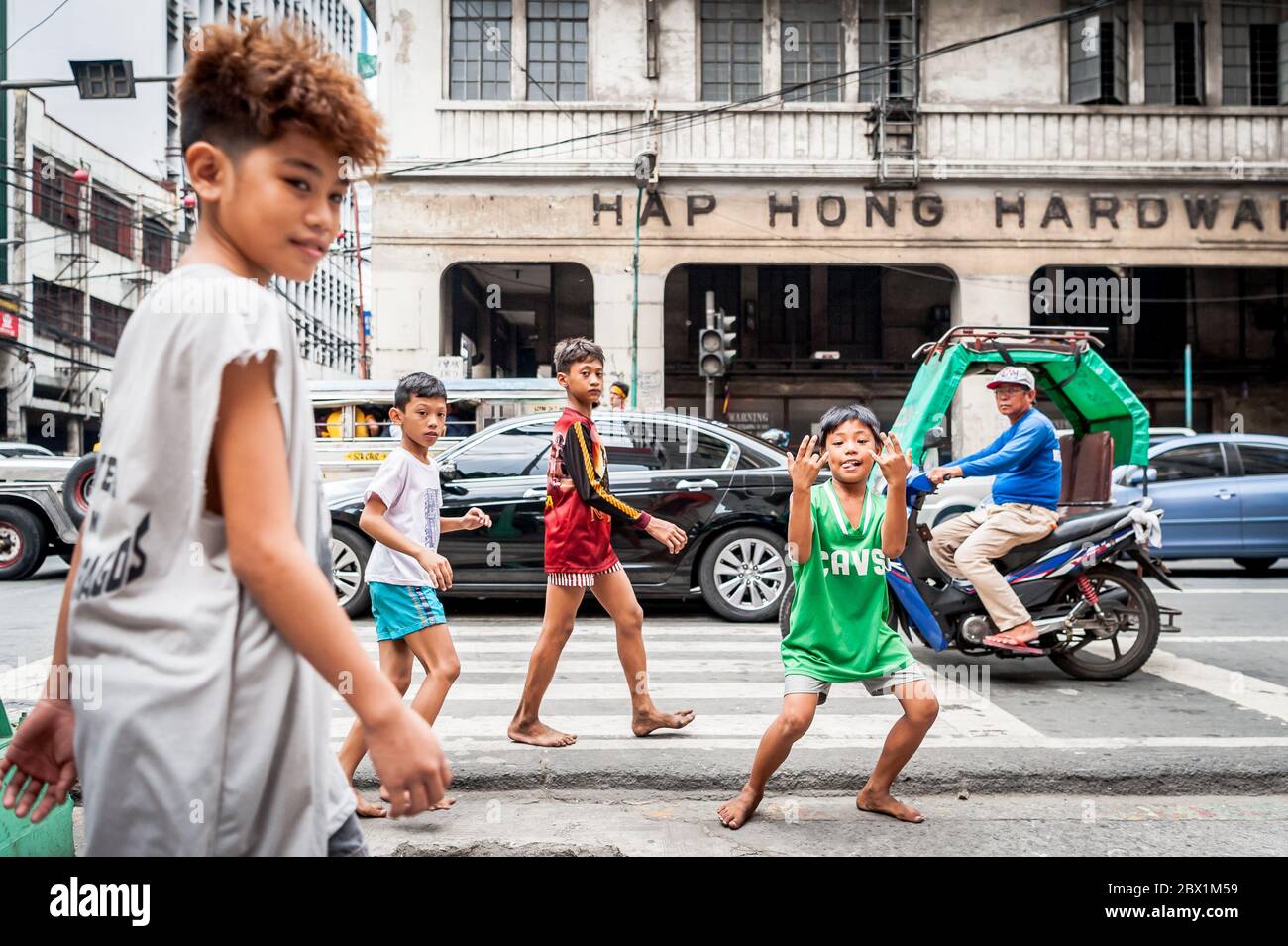 I poveri bambini filippini di strada giocano in un incrocio occupato nella città cinese, distretto di Binondo di Manila, le Filippine. Foto Stock