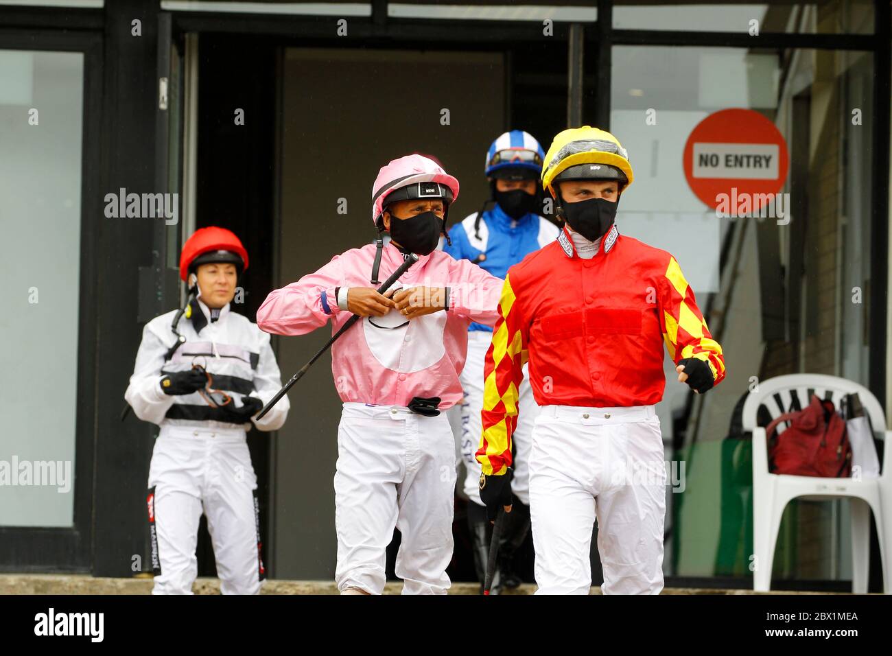 I jockey che indossano maschere facciali lasciano la sala di pesatura all'ippodromo di Newcastle. Foto Stock