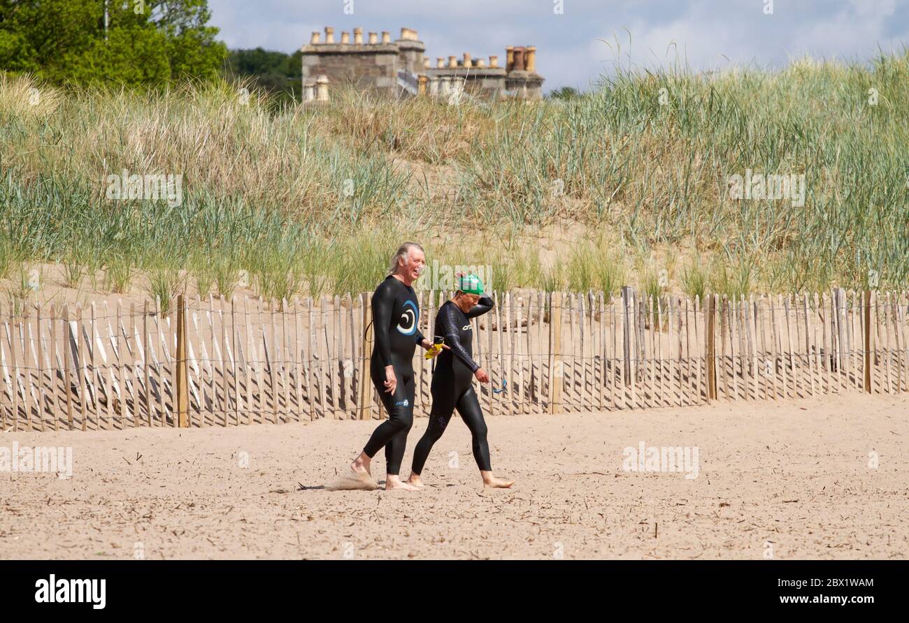 Dundee, Tayside, Scozia, Regno Unito. 4 Giugno 2020. Regno Unito Meteo: Una miscela di sole e nuvole insieme con docce sparse che si sfondano in tutta la Scozia nordorientale ha tenuto i beachgoers ed i bagnanti dal avventurarsi fuori alla spiaggia di Broughty Ferry a Dundee durante il blocco di Covid-19. Una coppia di mezza età che indossa suite con bagno privato è fuori per nuotare nell'estuario del fiume Tay. Credit: Dune Photographics/Alamy Live News Foto Stock