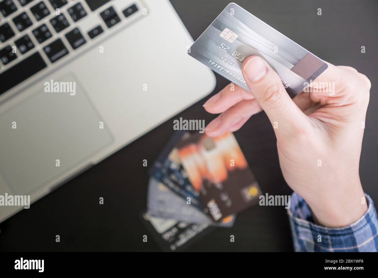Maschio di mani tenendo la carta di credito, computer portatile sul tavolo, shopping online concetto. Foto Stock