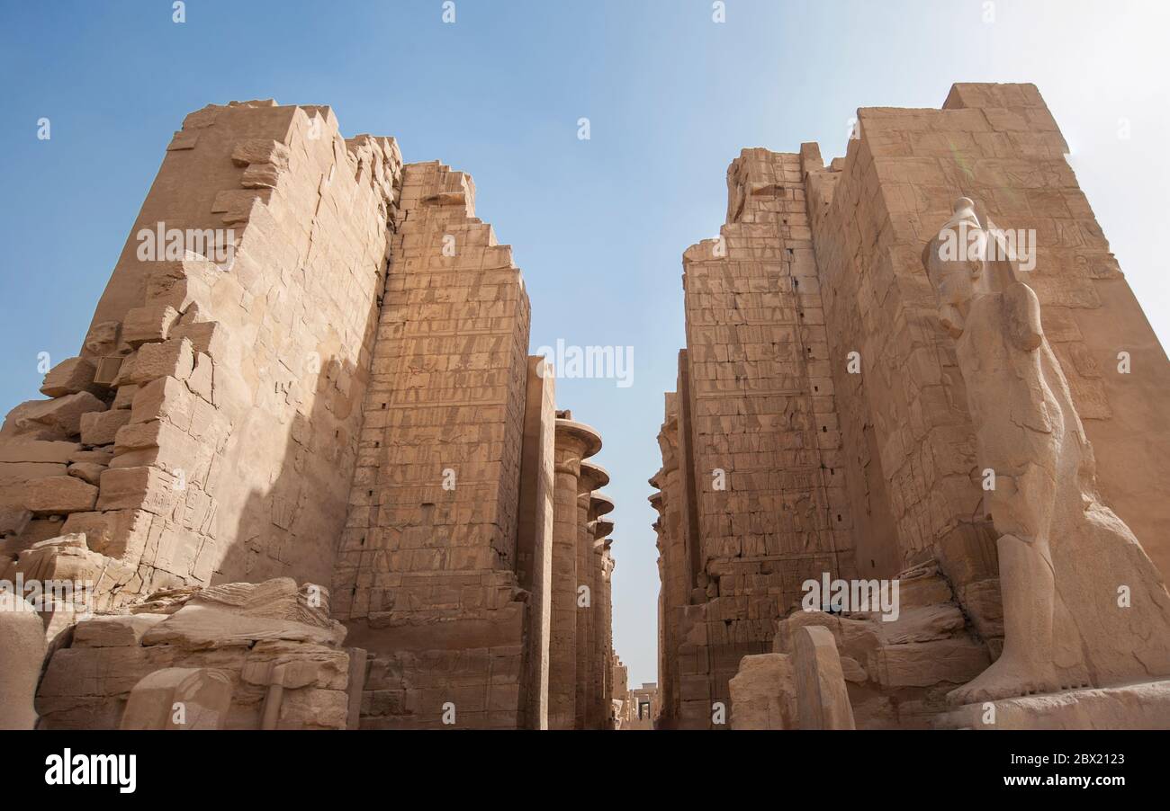 Grande pilone d'ingresso con statua di ramses II al tempio di Karnak in Luxor Egitto su sfondo blu cielo Foto Stock