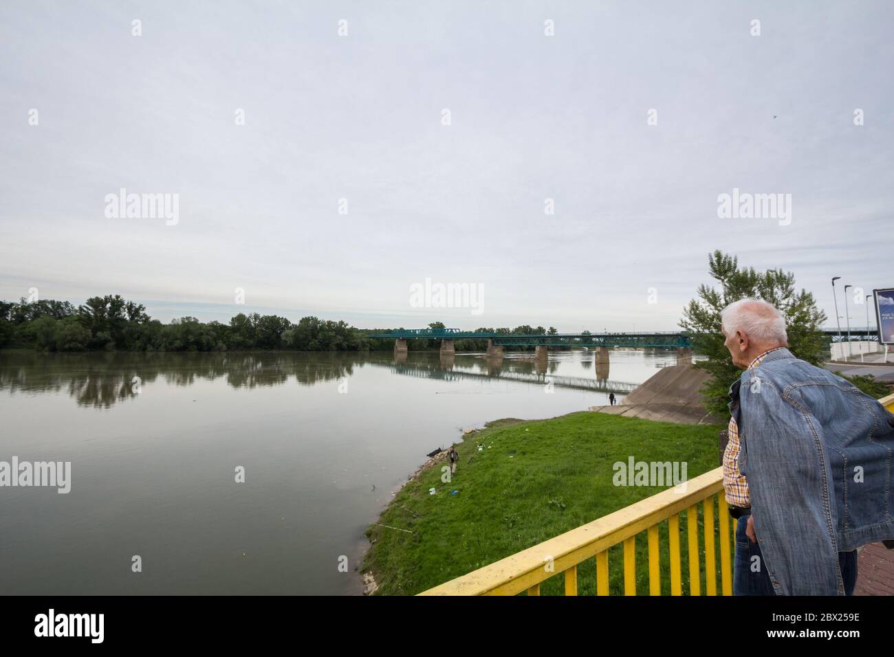 BRCKO, BOSNIA - 6 MAGGIO 2017: Anziano uomo che guarda un ponte di acciaio che attraversa il fiume Sava al confine tra Bosnia e Croazia, un'officia Foto Stock