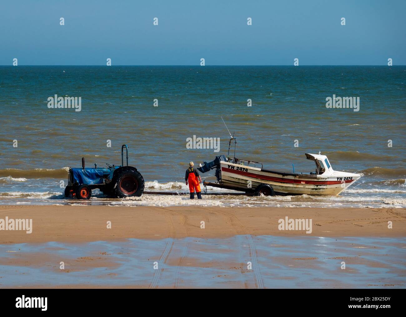 Pescatore che si prepara a trainare la sua barca da pesca di nuovo a riva. Foto Stock