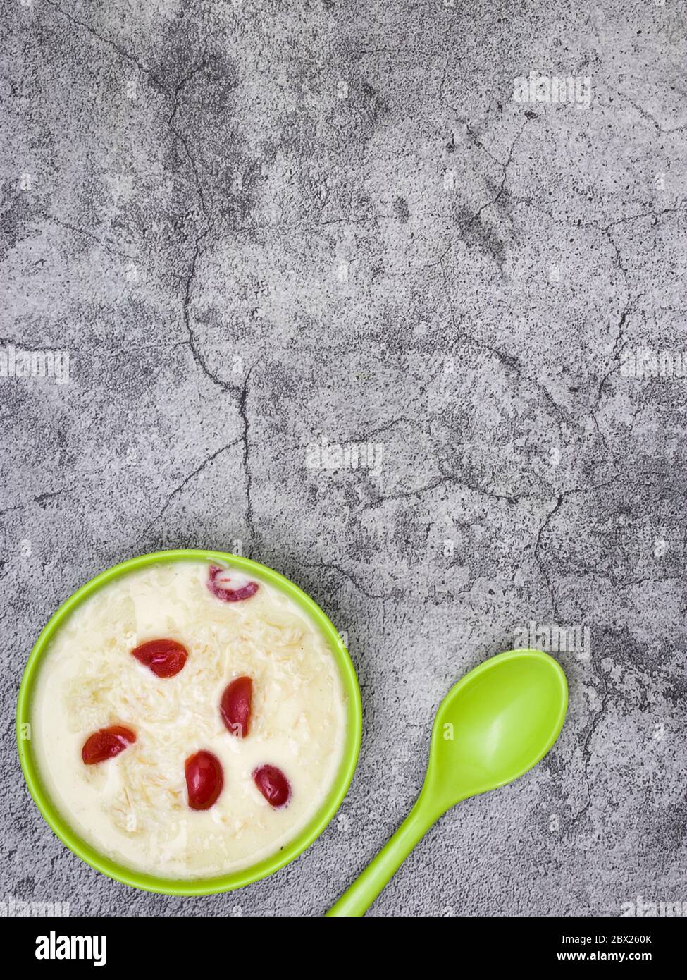 Sewai o kheer consumati in occasione di festival eid o indiani. Servito con condimenti di ciliegia rossa in una ciotola verde. Foto Stock