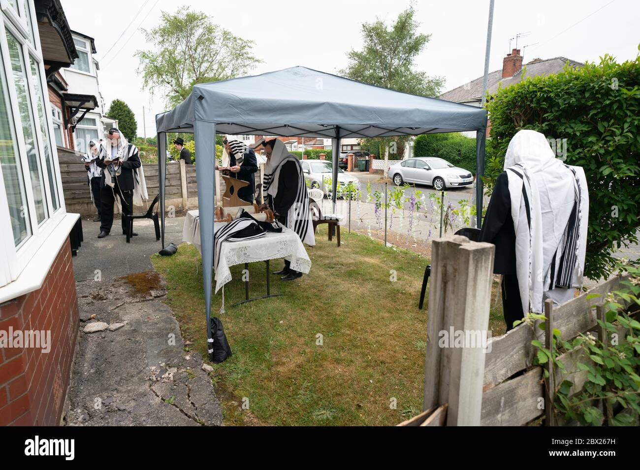 Manchester, Regno Unito. 4 Giugno 2020. Gli ebrei ortodossi conducono le loro preghiere mattutine nei giardini adiacenti di Salford in modo da rispettare le nuove regole che consentono a 6 persone di riunirsi in un giardino ma ancora di ottenere un minyan, un quorum di dieci adulti ebrei richiesto per alcuni obblighi religiosi, Manchester, Regno Unito. Credit: Jon Super/Alamy Live News. Foto Stock