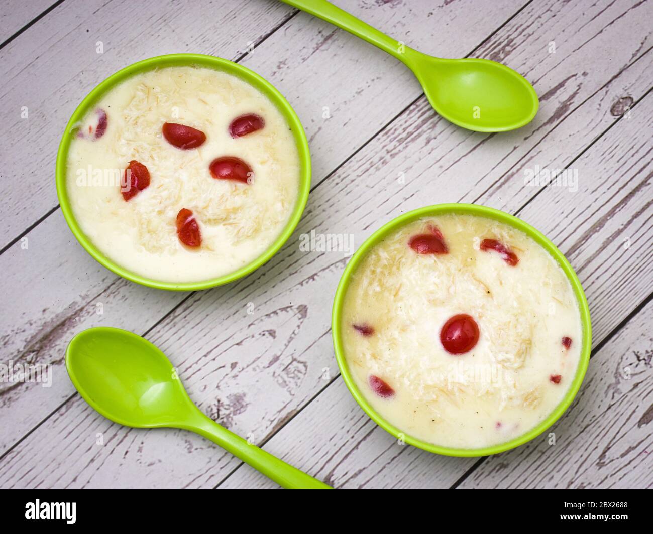 Sewai o kheer consumati in occasione di festival eid o indiani. Servito con condimenti di ciliegia rossa in una ciotola verde. Foto Stock