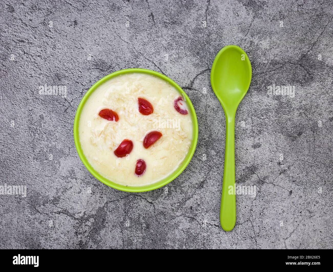 Sewai o kheer consumati in occasione di festival eid o indiani. Servito con condimenti di ciliegia rossa in una ciotola verde. Foto Stock